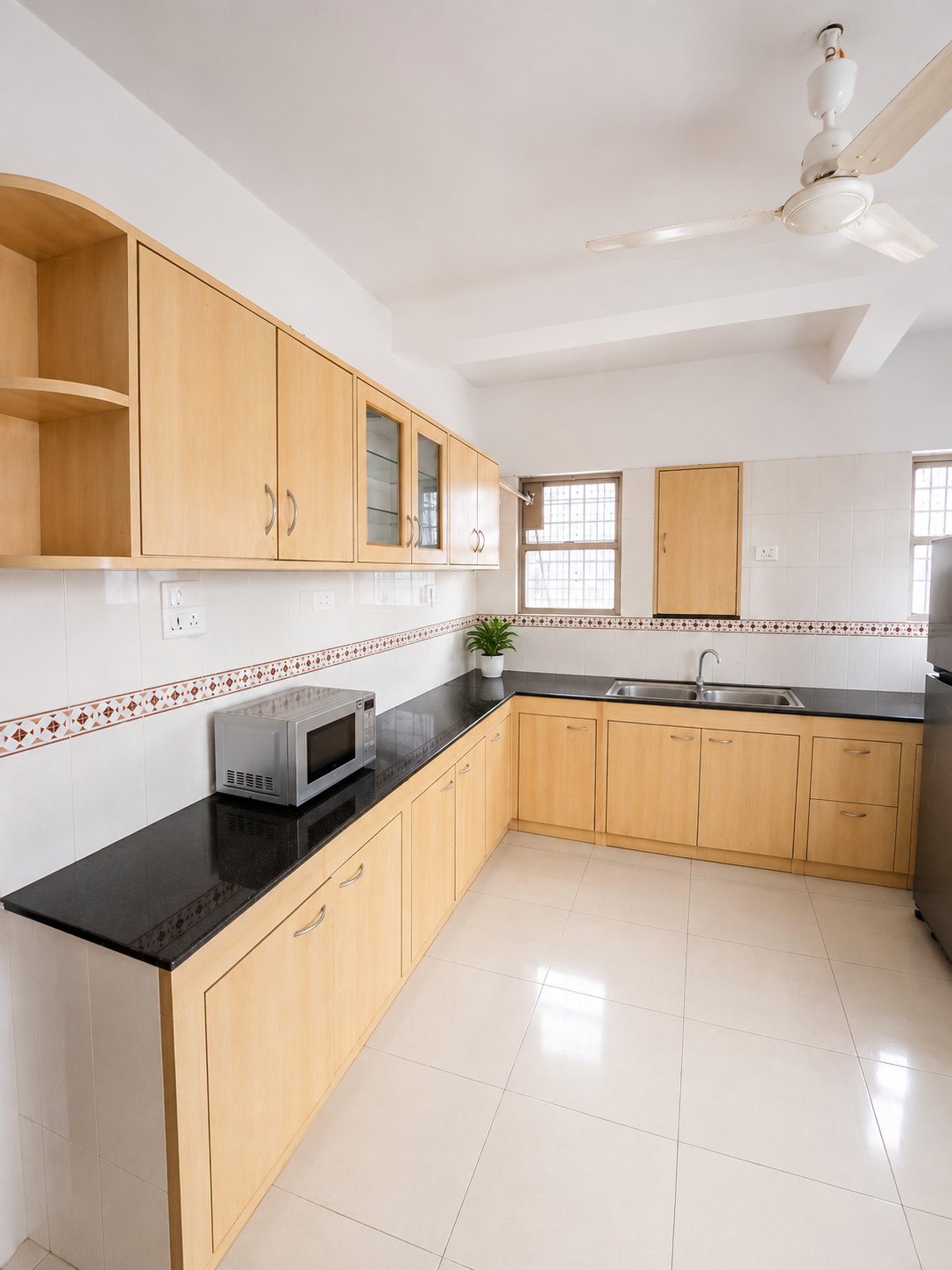Modern shared kitchen with granite counters, microwave and ample storage cabinets — Go GenZ Stays girls PG